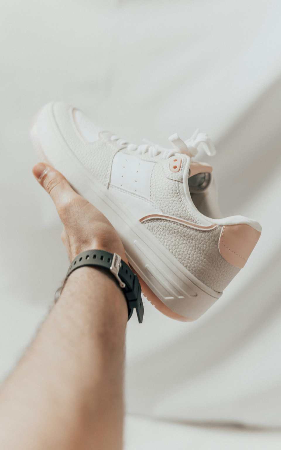 une personne tenant une chaussure de tennis blanche